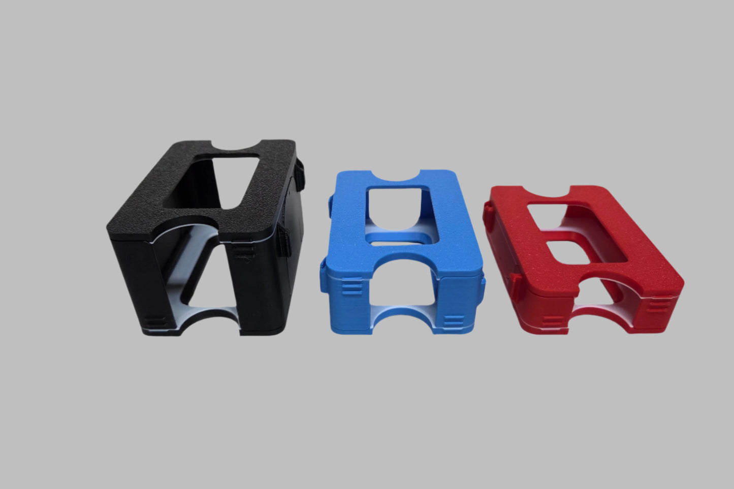 Three plastic deck boxes in black, blue, and red on a white background